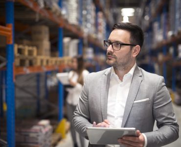 Manager in a warehouse holding a tablet.